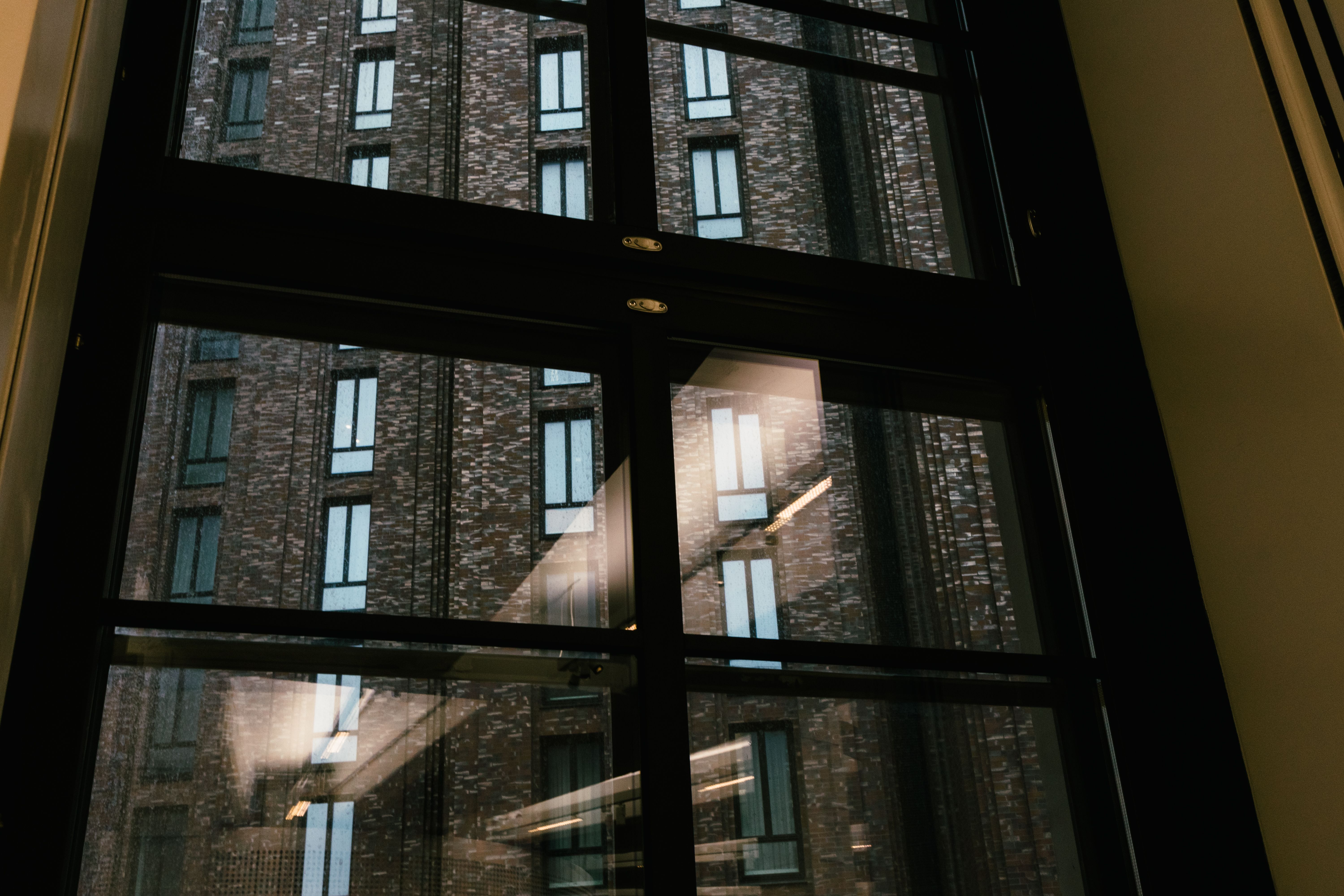 View of a brick building through an urban office window with reflections.
