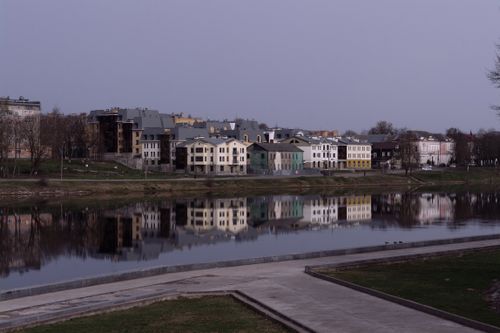 Free Beautiful riverside homes reflecting in the tranquil water under a soft sky. Stock Photo