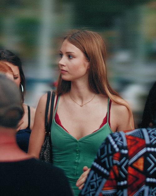 Free Young woman in Berlin street, wearing green dress, amidst city crowd. Stock Photo