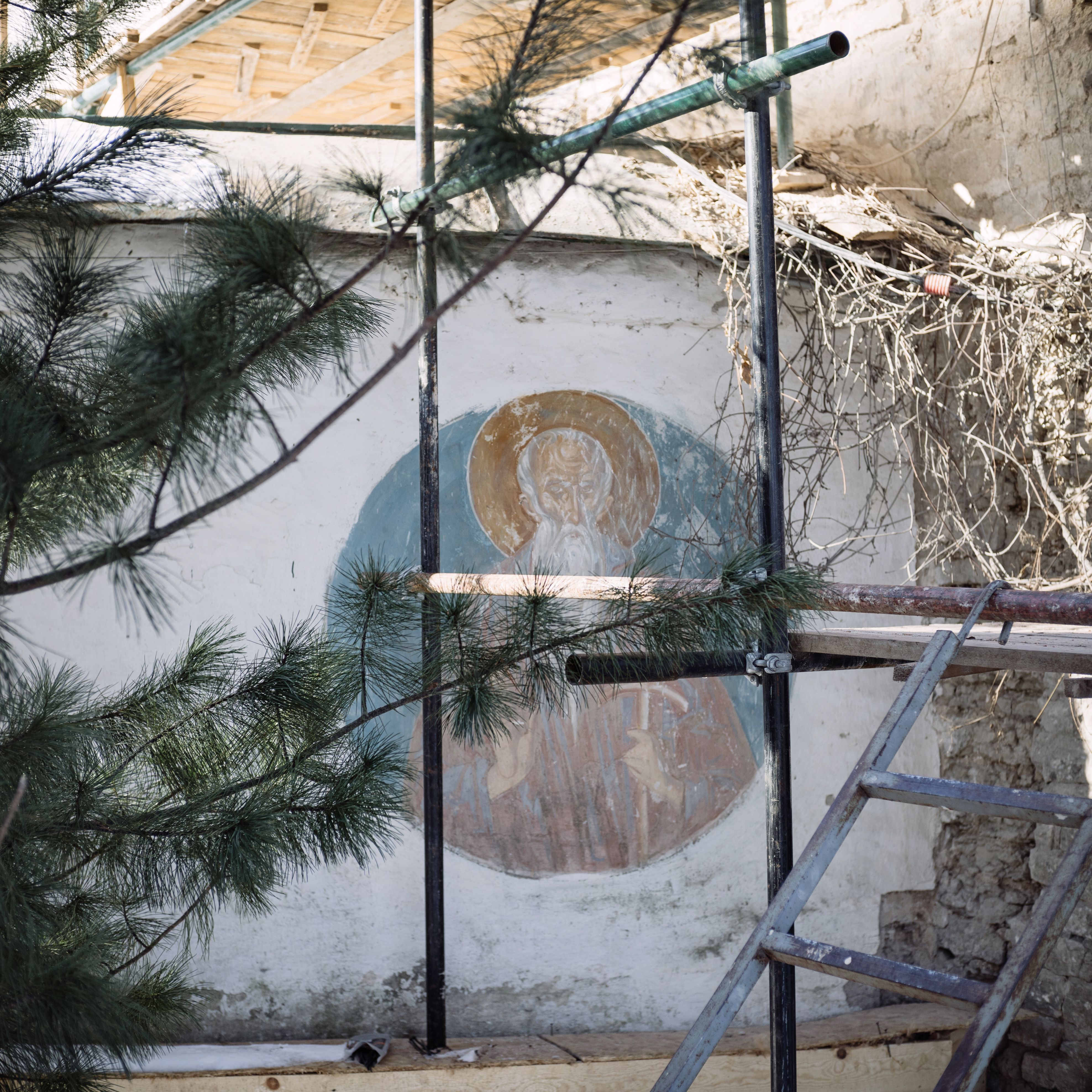 Outdoor scene of a restoration project on a historic religious mural.