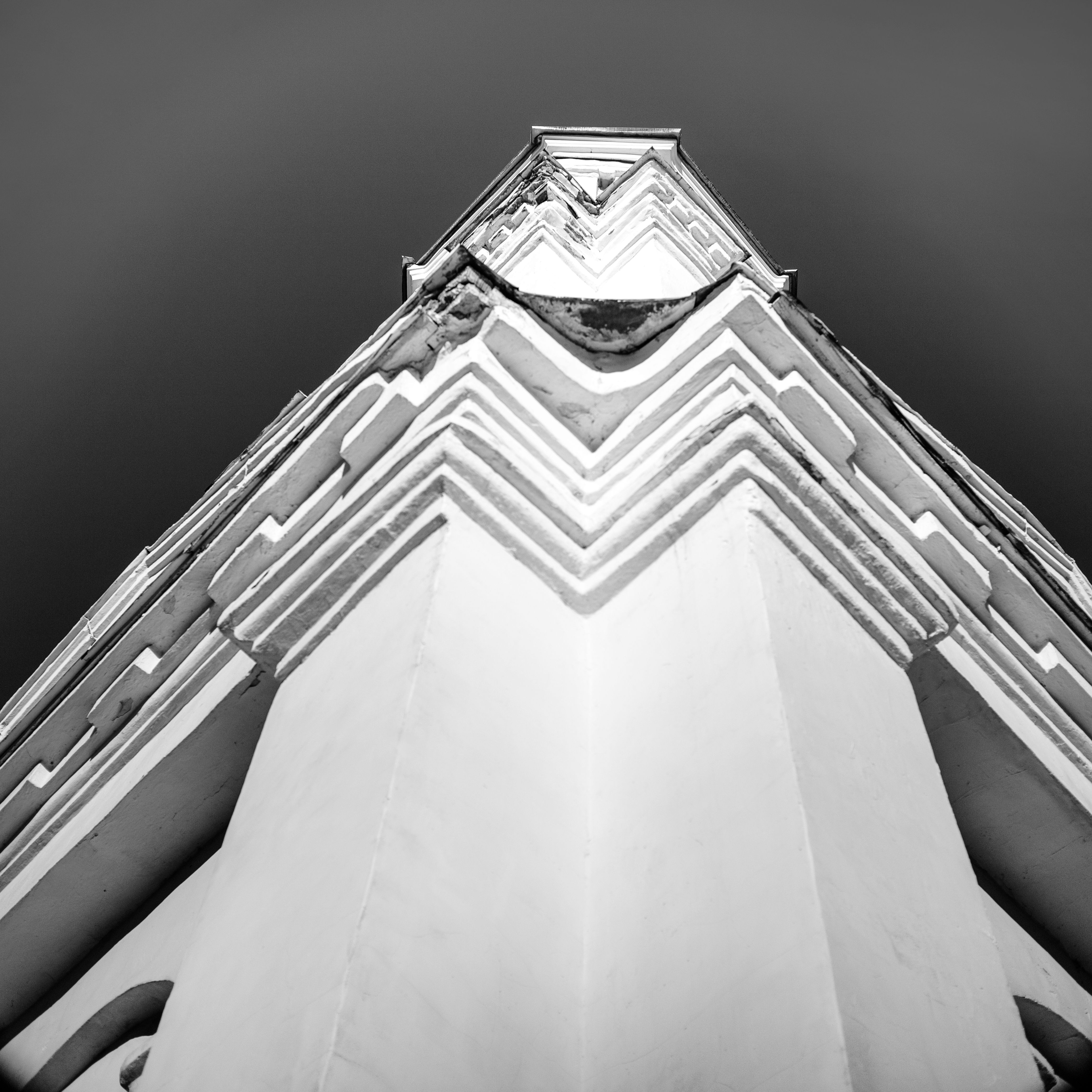 A detailed black and white close-up of a building's architectural corner, showcasing patterns and symmetry