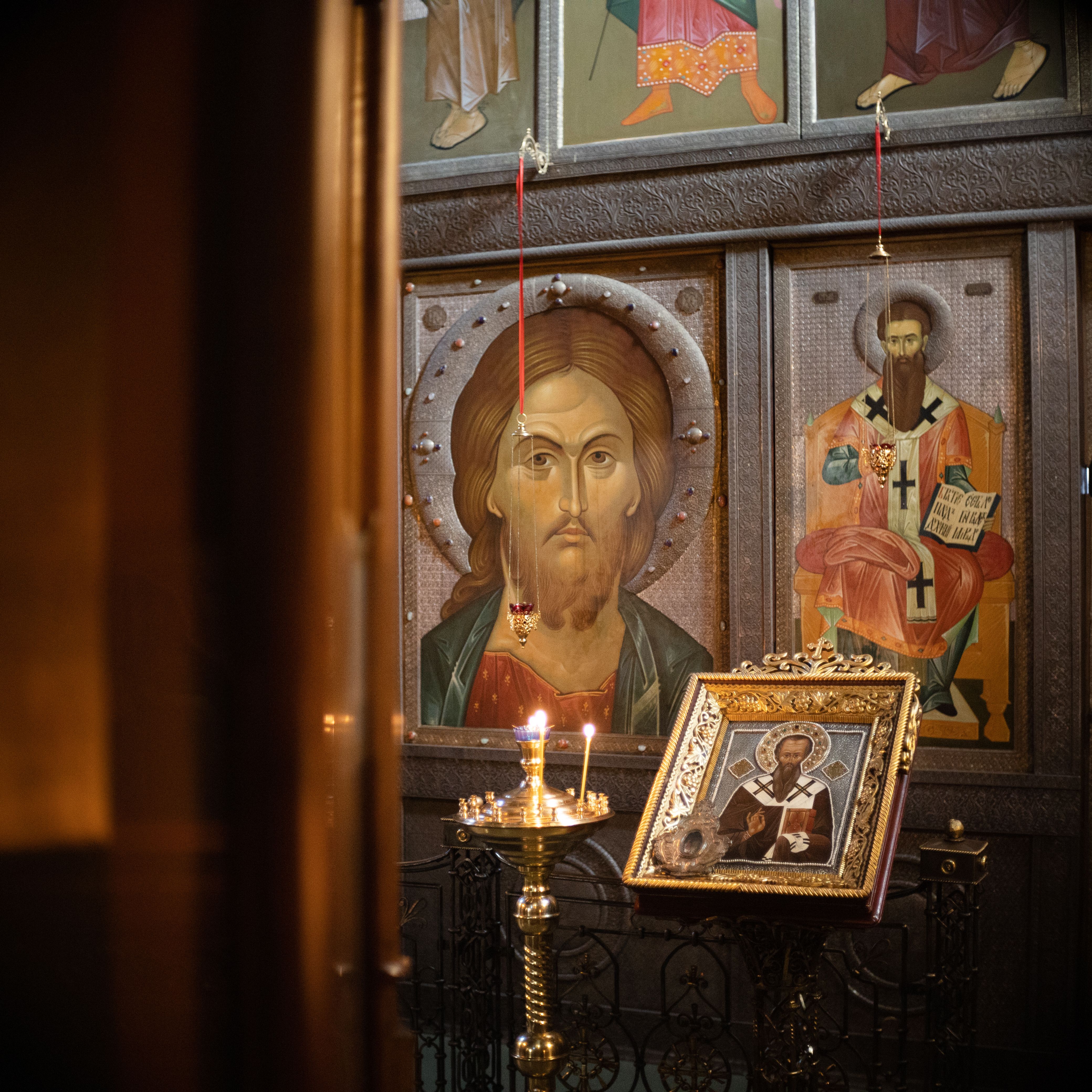 Religious icons and a candle holder in an Orthodox church setting.