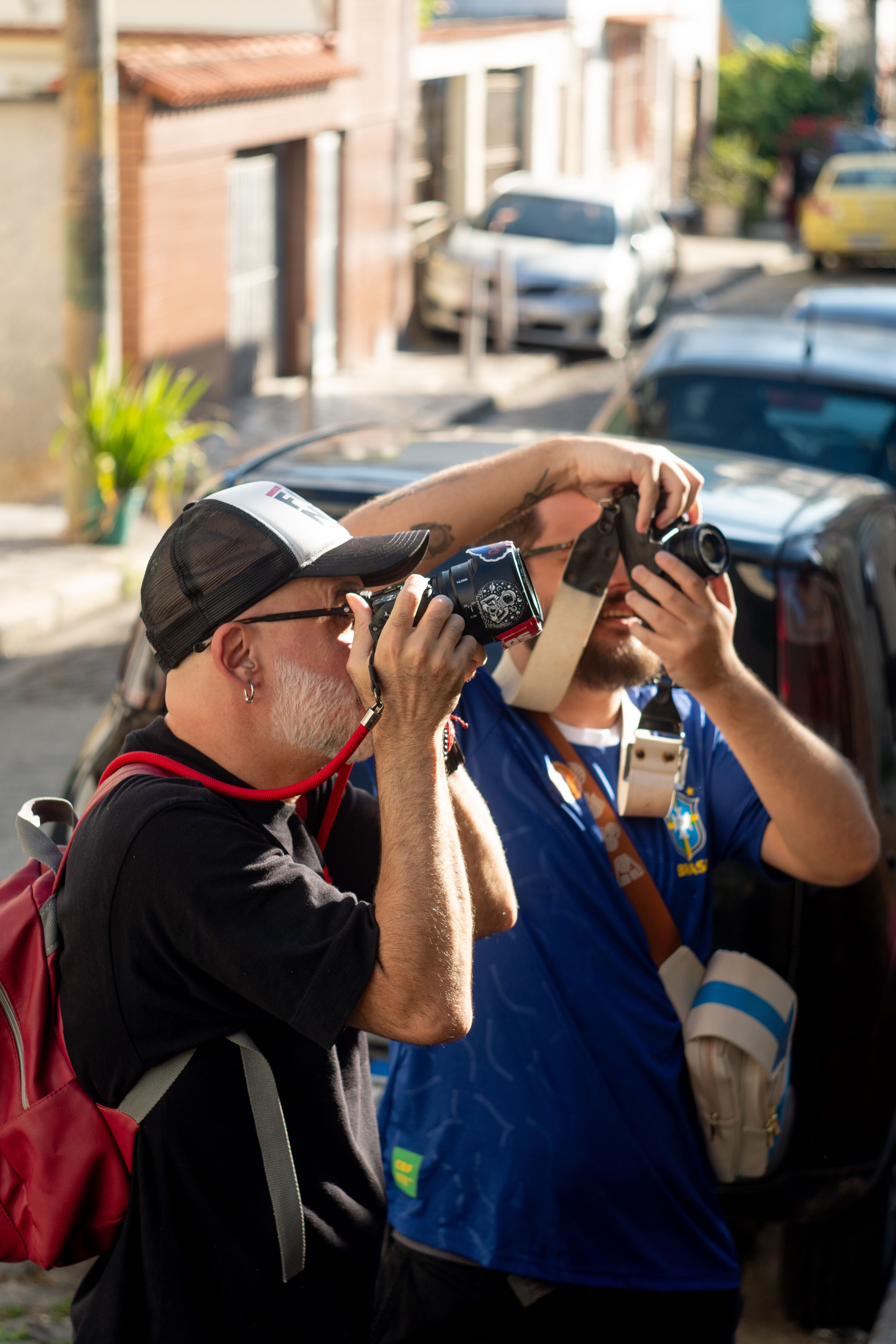 Two photographers capturing candid moments on a sunny street, showcasing urban culture.