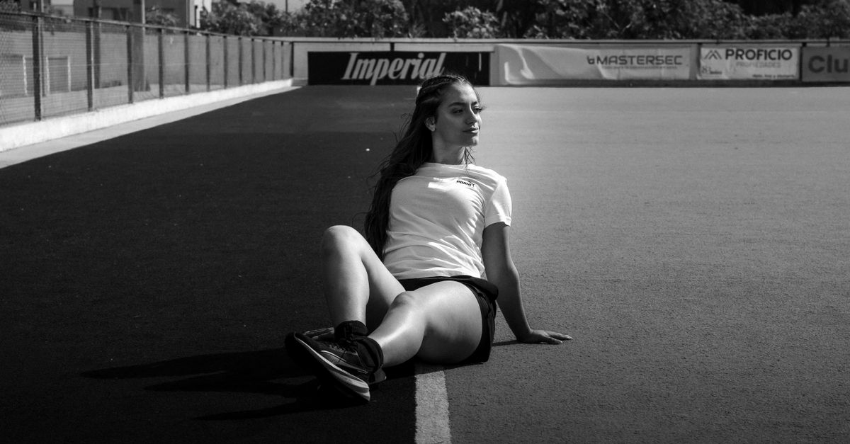 Young girl watching a female athlete with wide eyes, holding a sign