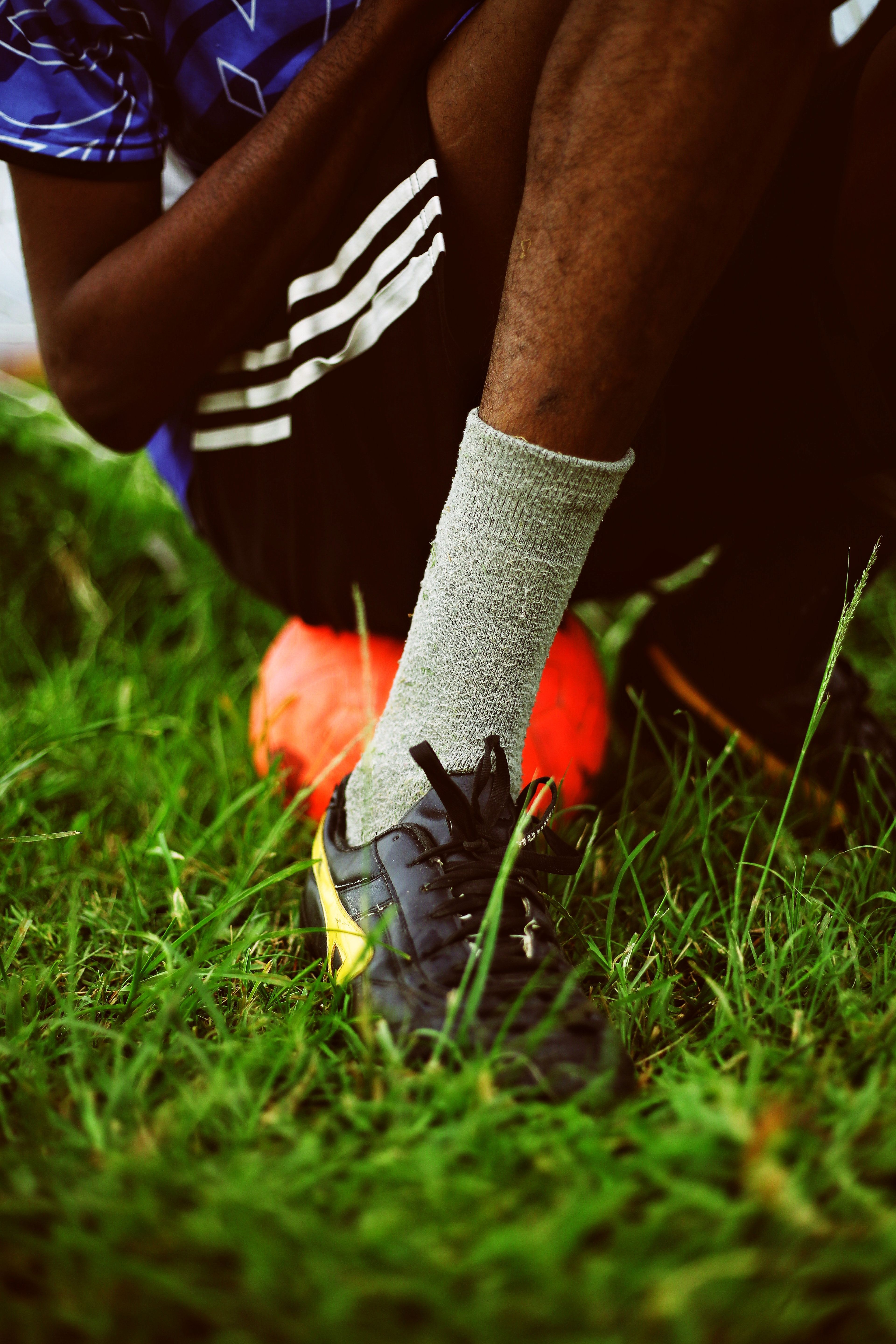 An athlete preparing for a soccer match by tying their shoe on a vibrant green field, showcasing determination.