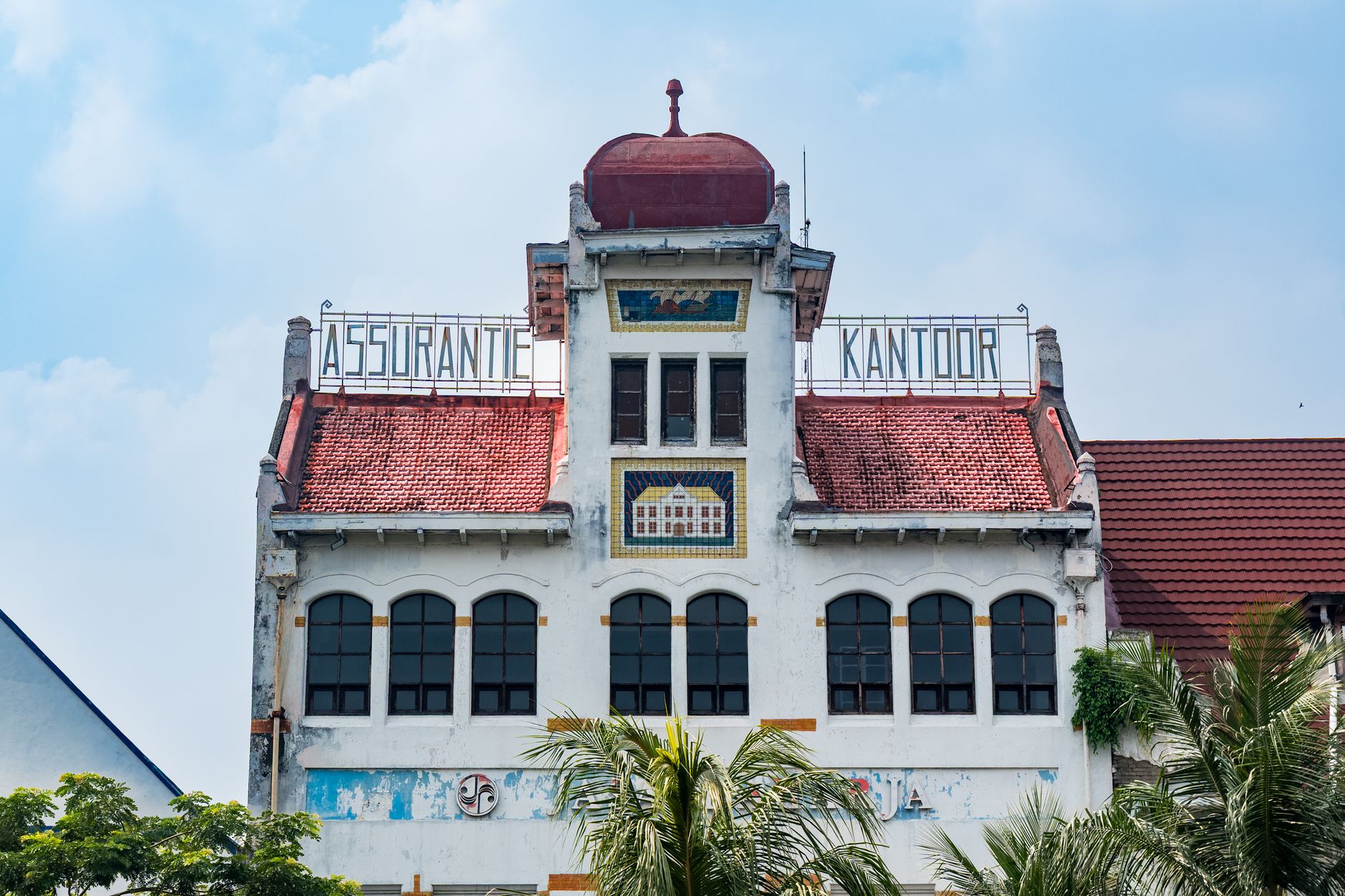 Front view of a historic colonial building in Jakarta with 'Assurantie Kantoor' signage.