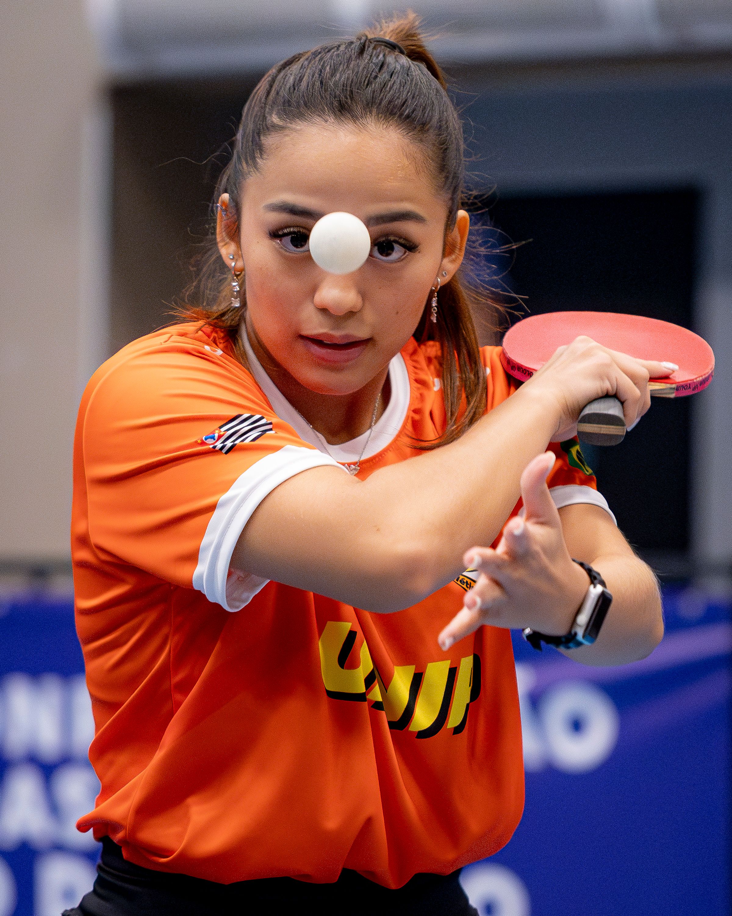 Focused female table tennis player in action, eyeing the ball intently.