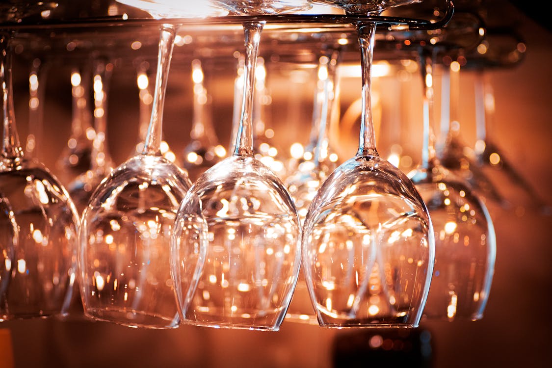 Glowing glassware hanging on drying rack in restaurant at night