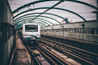 地铁列车行驶在高架铁路轨道上，穿过现代建筑林立的城市环境