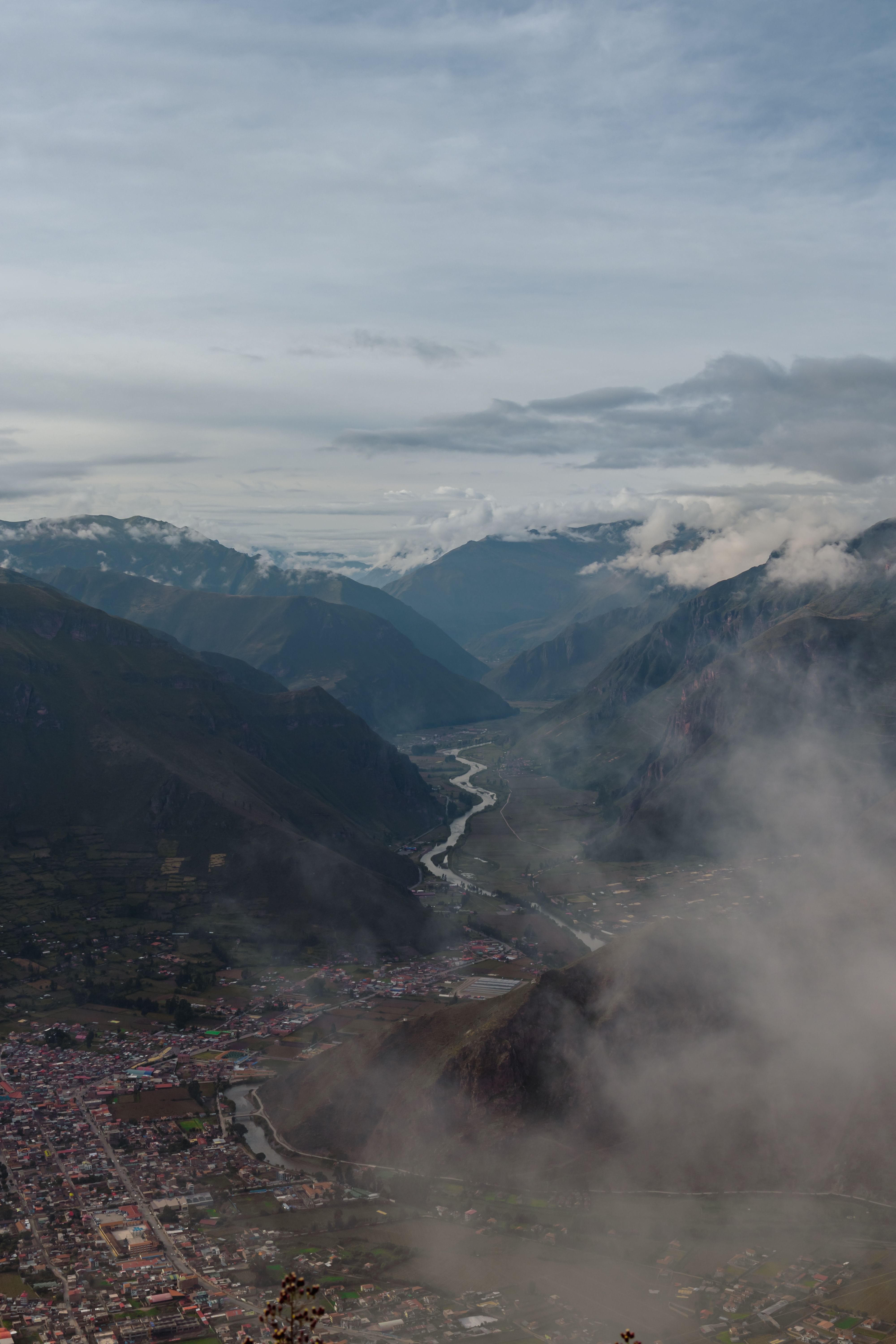Aerial view of a misty mountain valley with winding river and scenic clouds.