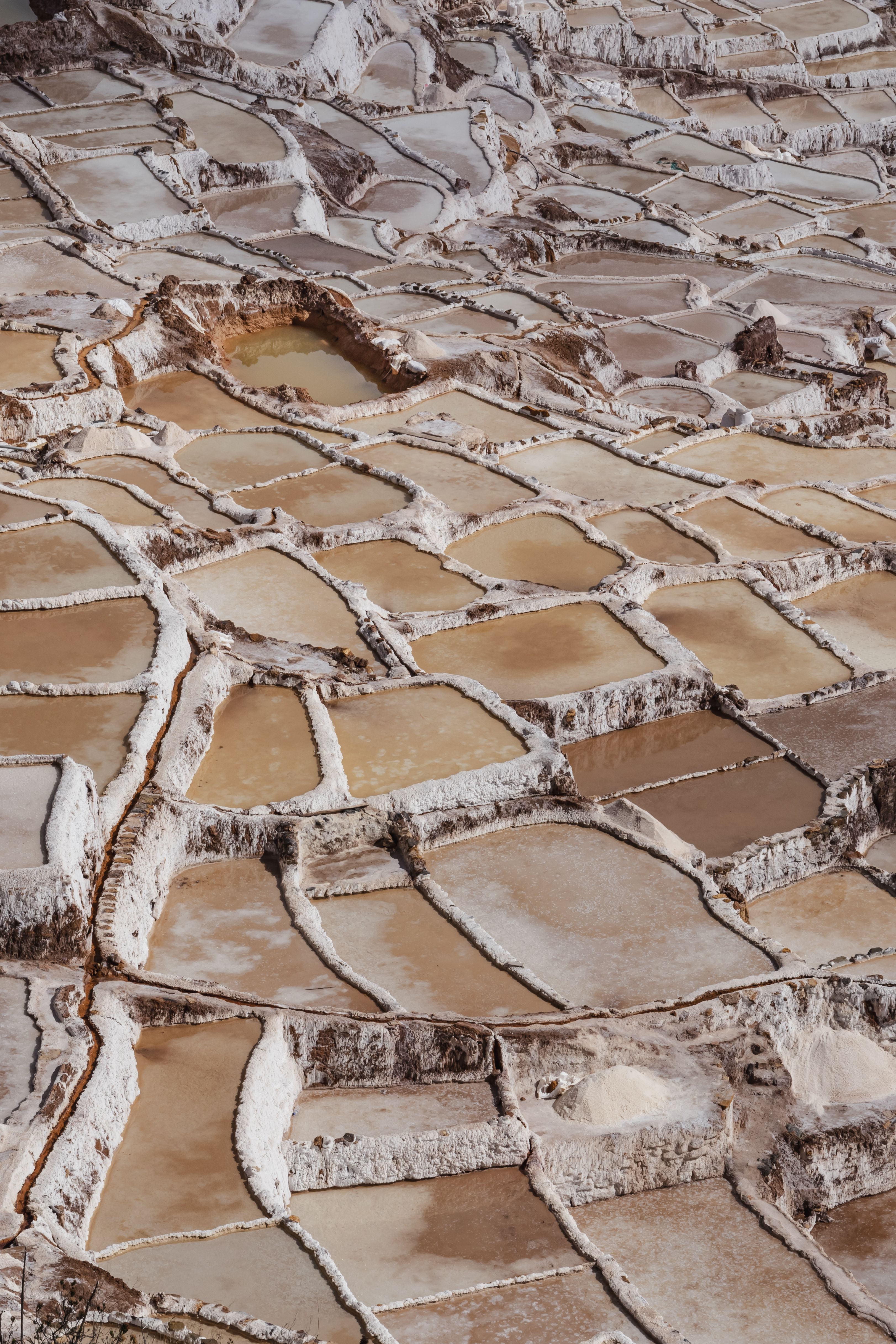Aerial view of geometric salt pans in Maras, Peru, showcasing traditional salt mining.