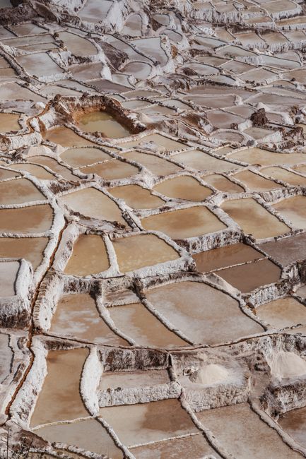 Aerial view of geometric salt pans in Maras, Peru, showcasing traditional salt mining.