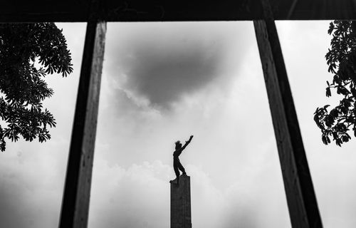 Free Silhouette of a statue at Monas in Jakarta framed by trees and a cloudy sky. Stock Photo