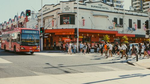 Free Vibrant street view of Burwood Hotel, bustling with pedestrians and a red bus in Burwood, NSW, Australia. Stock Photo
