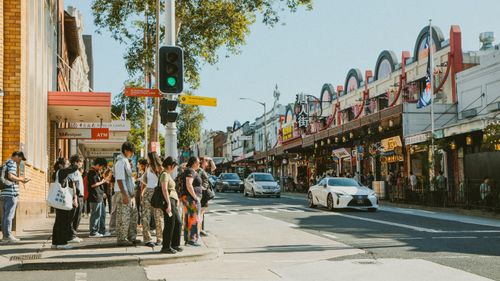 Free A bustling urban street with diverse pedestrians waiting at a crosswalk. Stock Photo