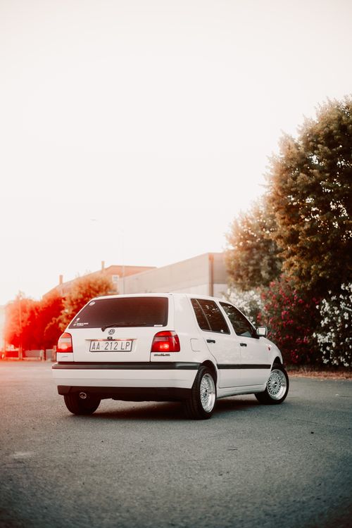 Free A vintage white car parked on a city street during sunset, with warm tones and retro style. Stock Photo