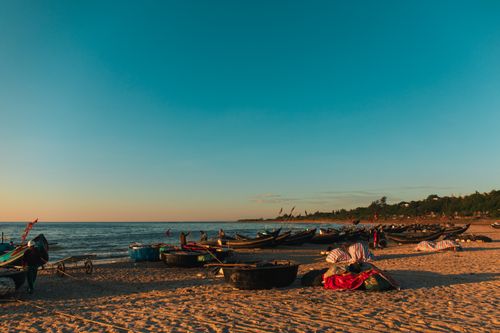 Free Serene Quảng Trị beach with traditional fishing boats at sunset, capturing local culture and beauty. Stock Photo