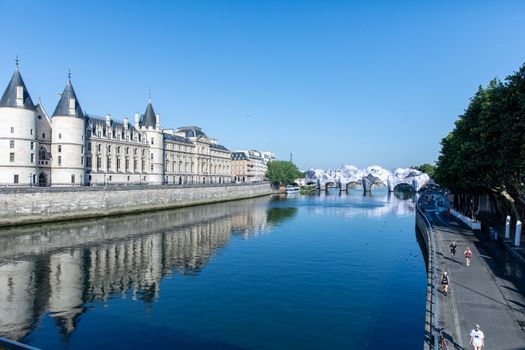 A picturesque view of La Conciergerie along the Seine River in Paris under a clear blue sky.