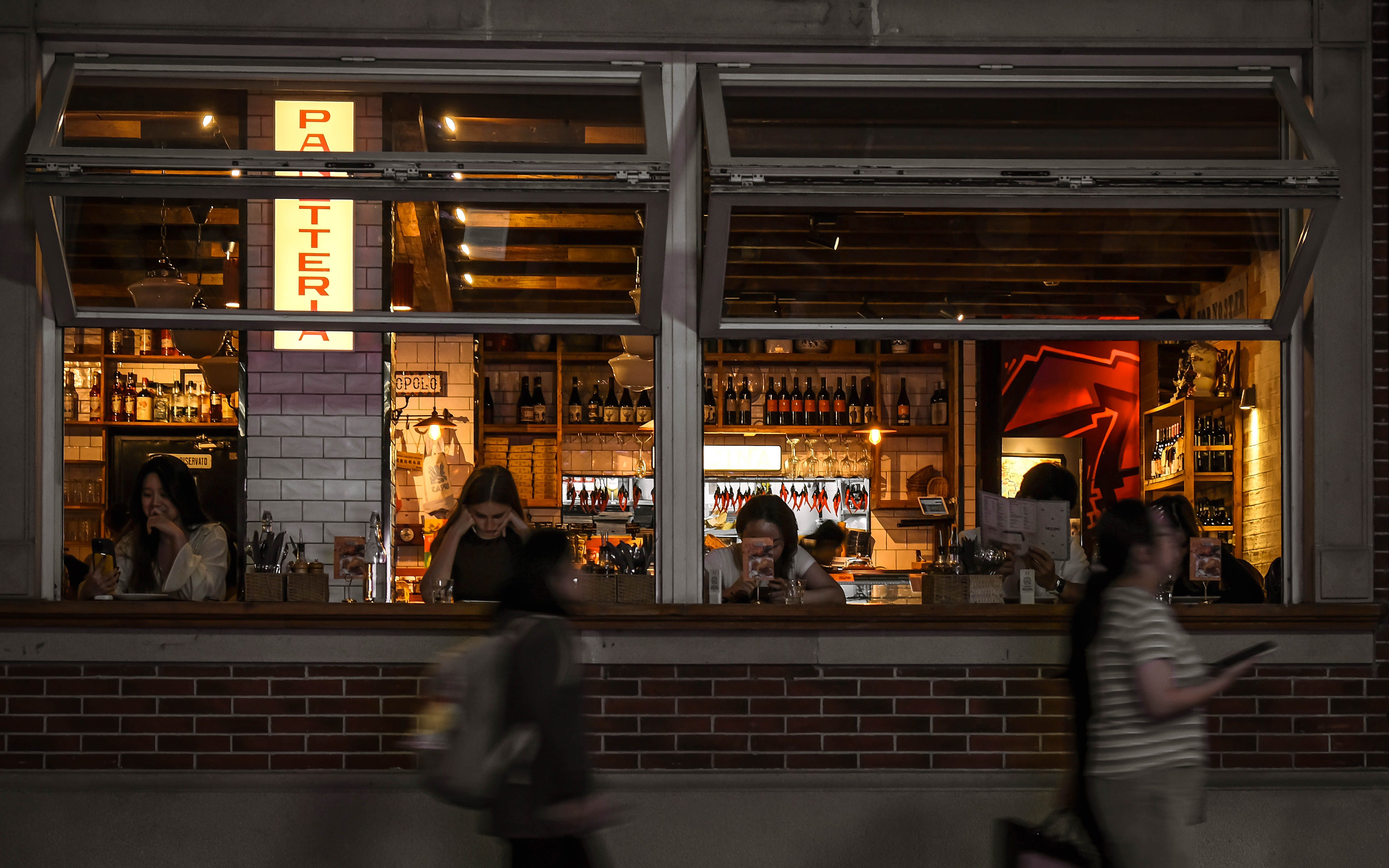 Warm, lively night inside a cozy urban pizzeria with diners and amber lighting, capturing a bold and confident atmosphere