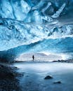 一位探险家站在冰岛闪闪发光的蓝色冰洞中，场景十分迷人