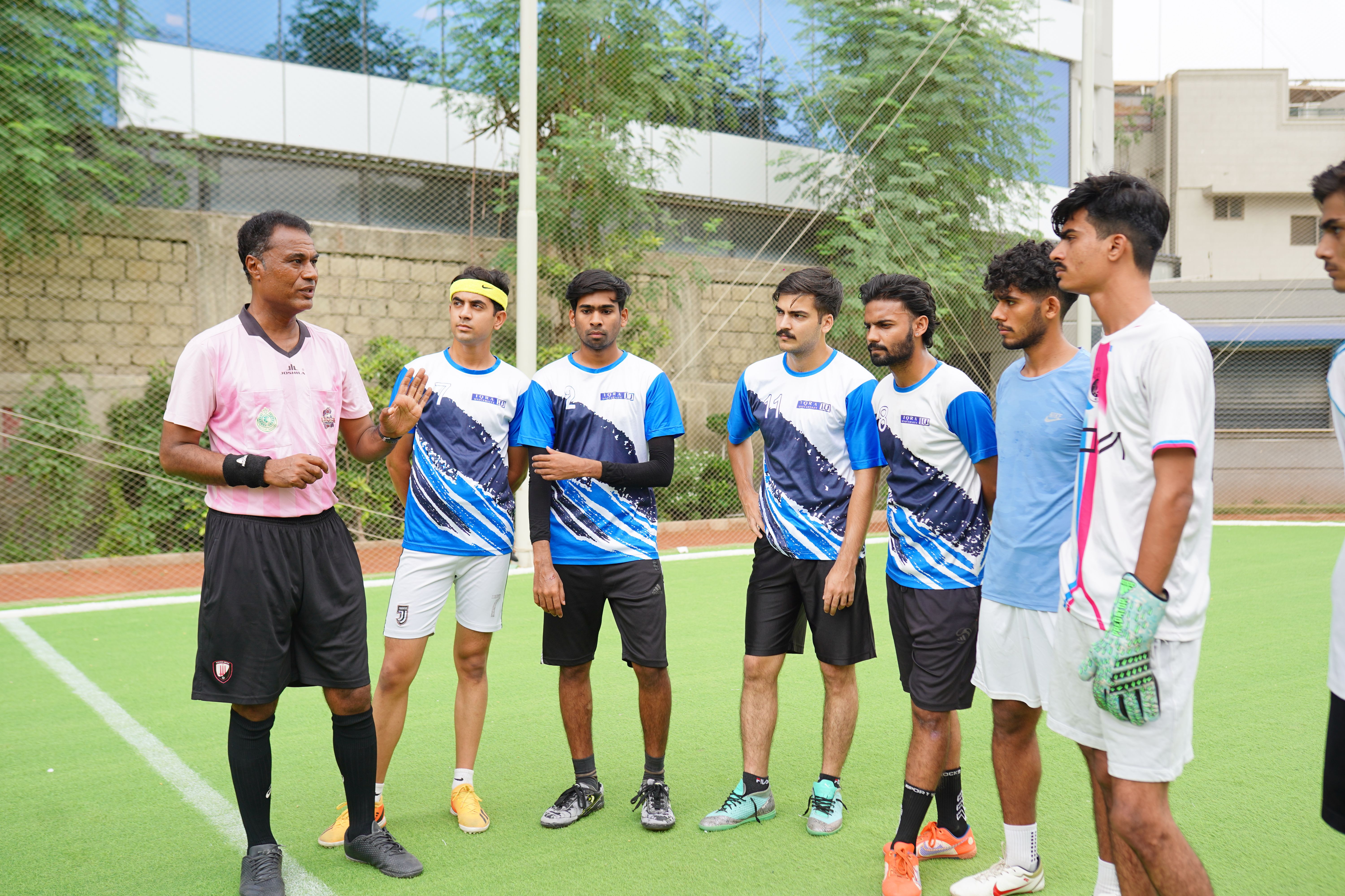A soccer coach gives instructions to young players during a practice session outdoors on a sunny day.