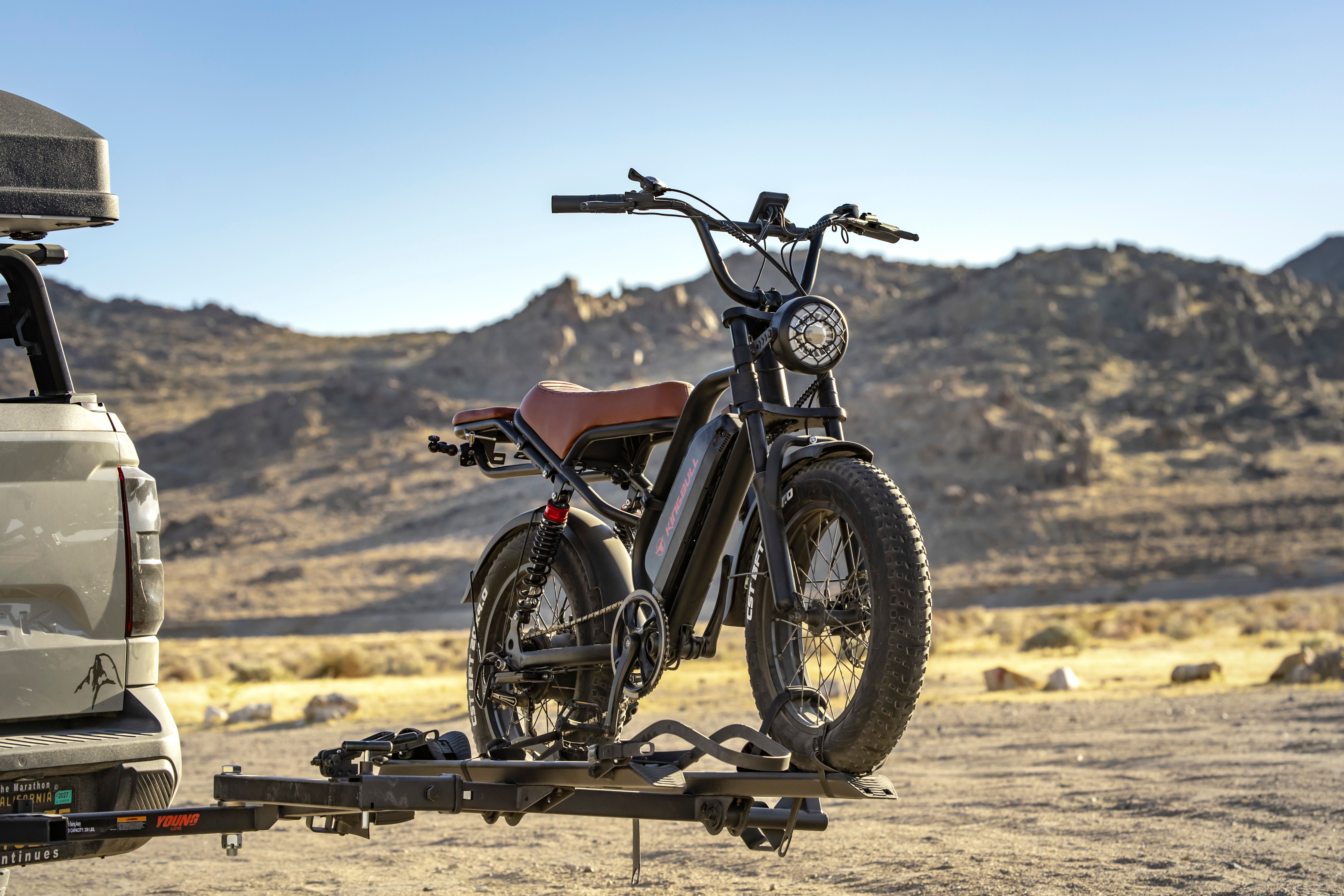 Electric bike mounted on a vehicle rack in a desert landscape.