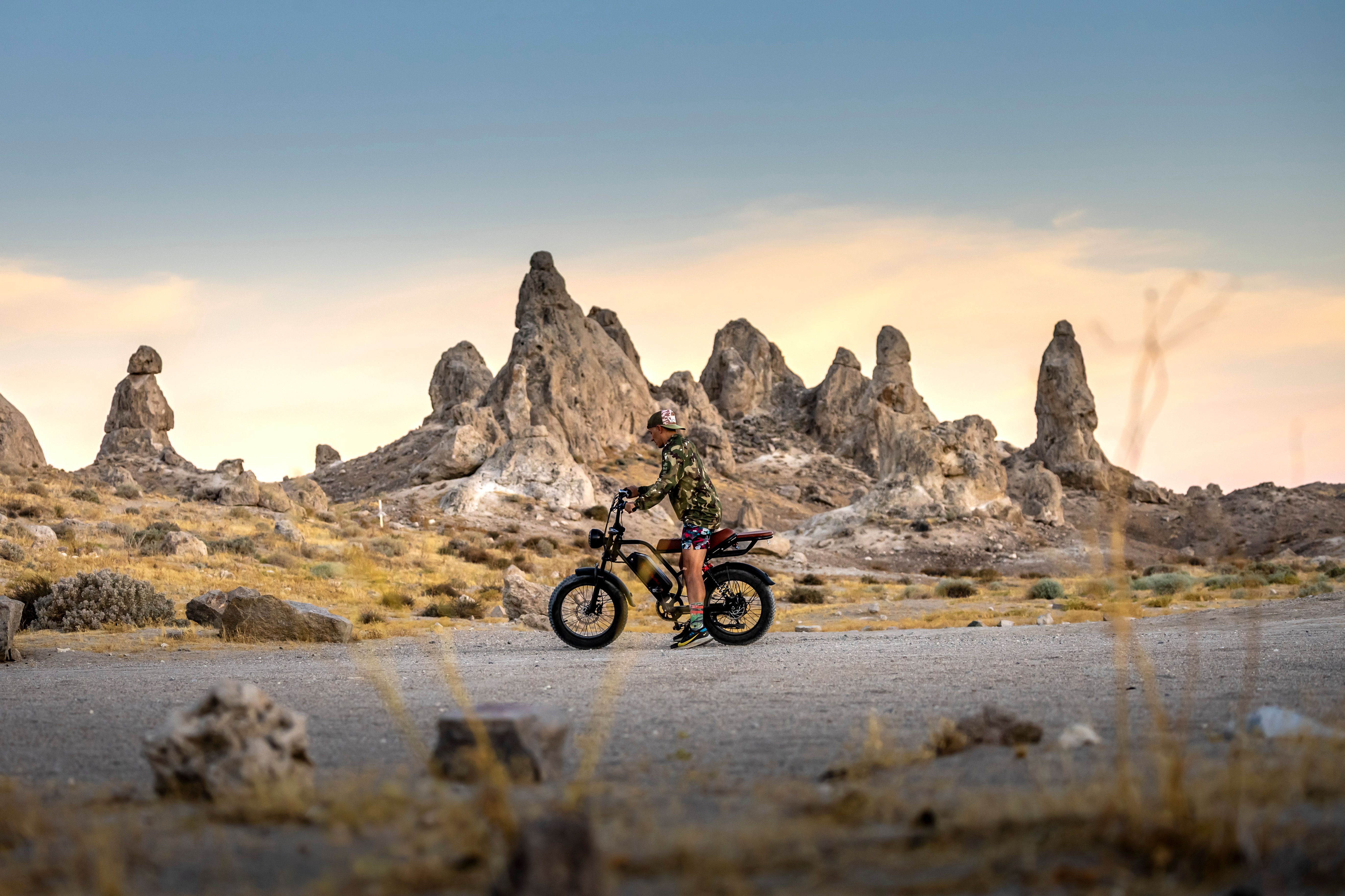 Rider on an electric bike traversing a desert landscape with striking rock formations.