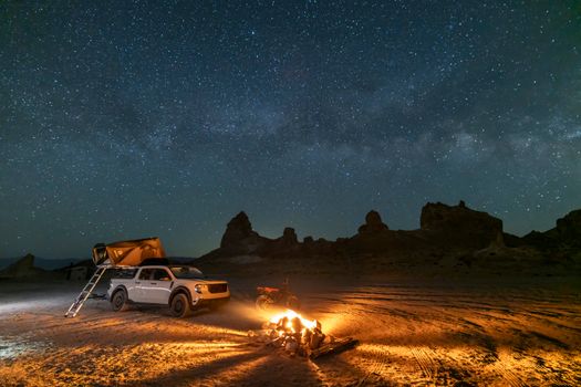 A serene desert camping scene with a tent, campfire, and starry Milky Way sky.