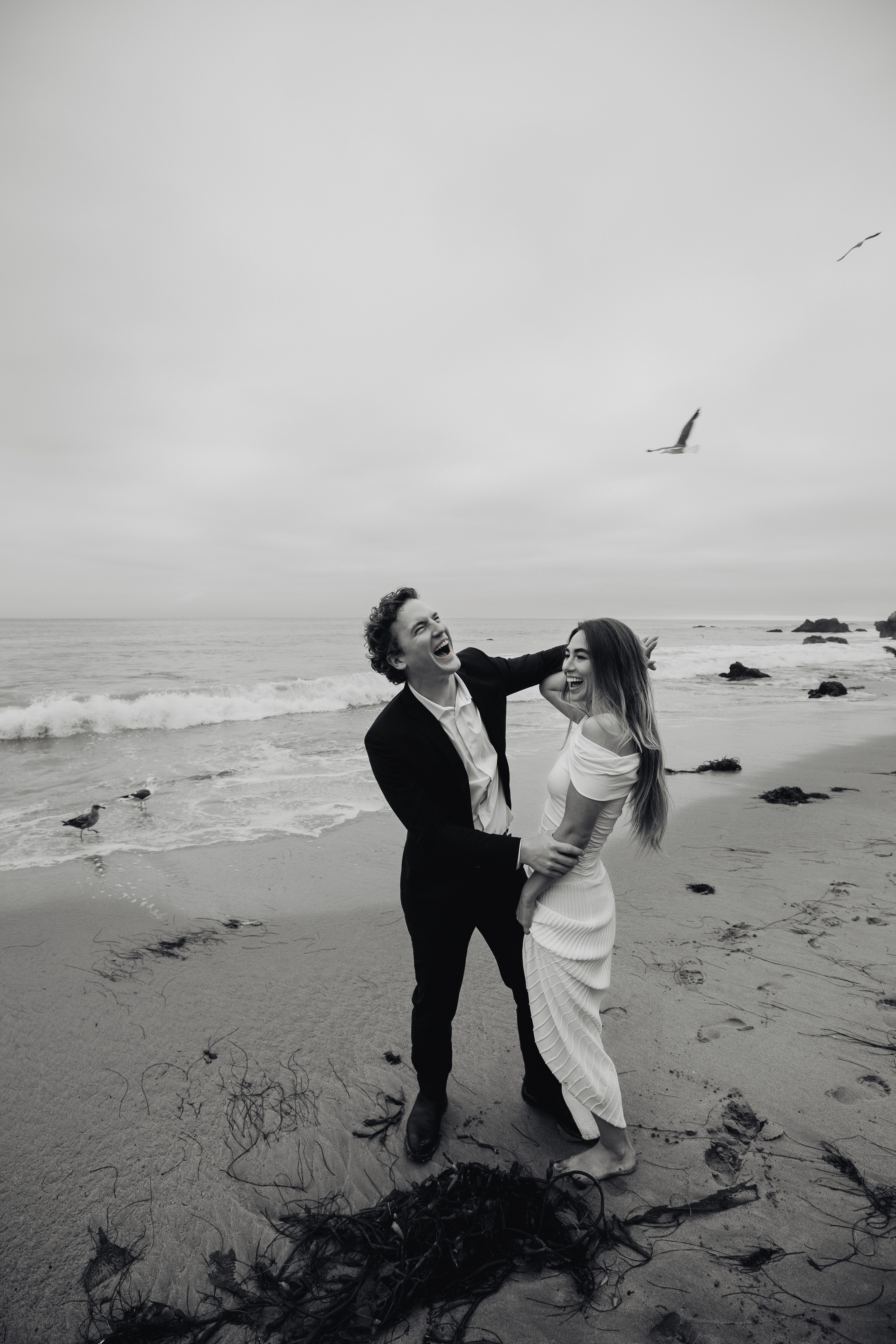 A joyful couple shares a moment on a beach in Los Angeles, perfect for wedding themes.