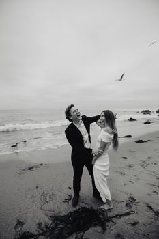 A joyful couple shares a moment on a beach in Los Angeles, perfect for wedding themes.