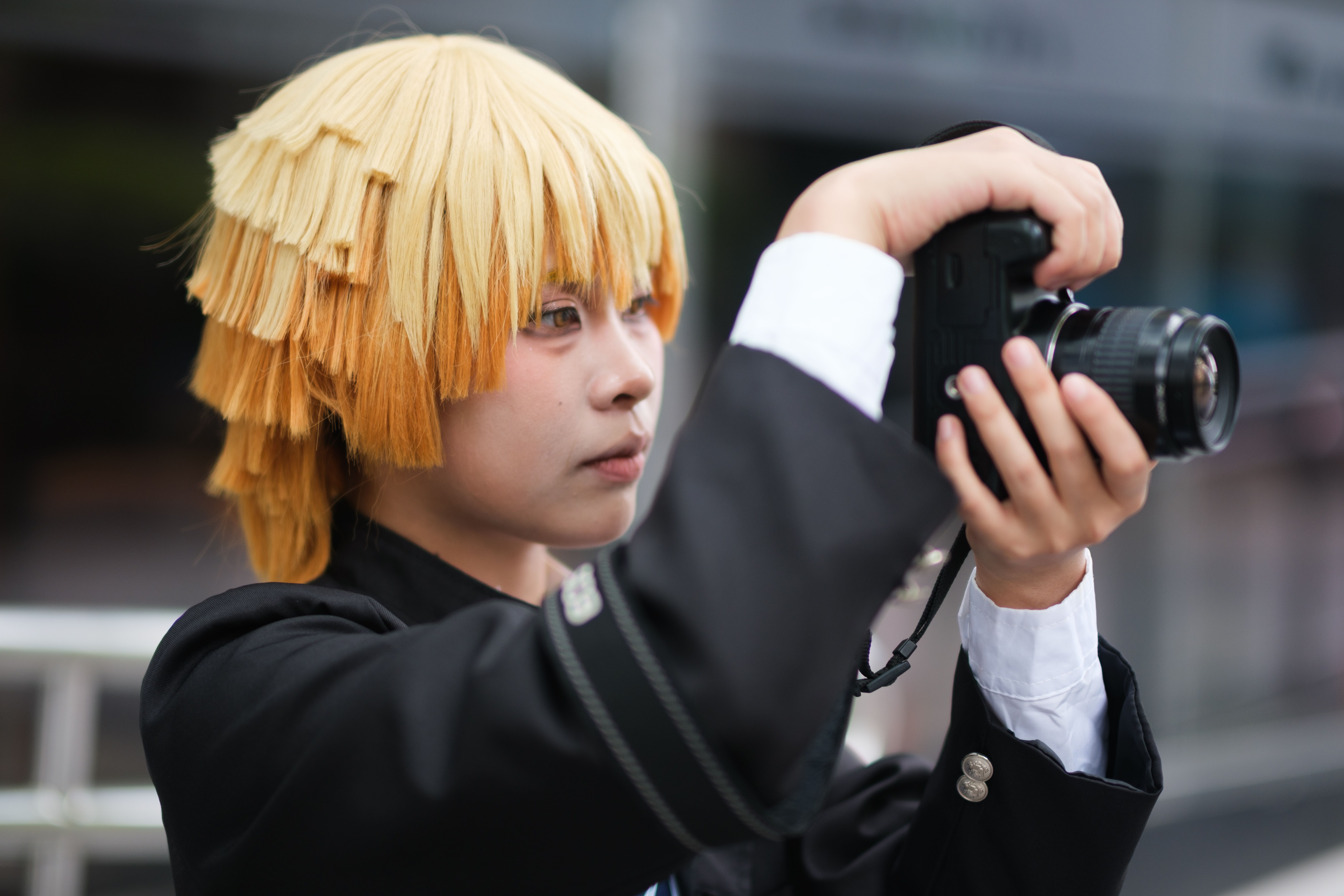 コスプレ衣装を着た若者が、屋外でカメラを使って写真を撮っている。