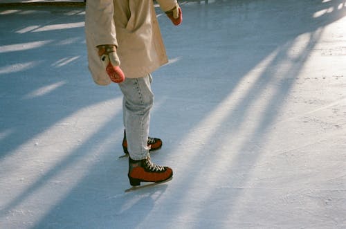 Безликая женщина в форме на коньках на катке при дневном свете