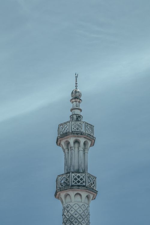 Free A detailed view of an ornate minaret standing tall against a clear, blue sky. Stock Photo