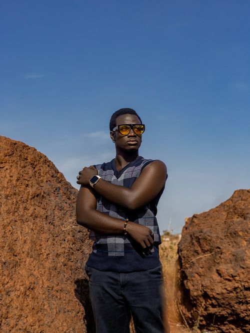 Free Stylish man wearing sunglasses poses confidently among rugged rocks under a clear sky. Stock Photo