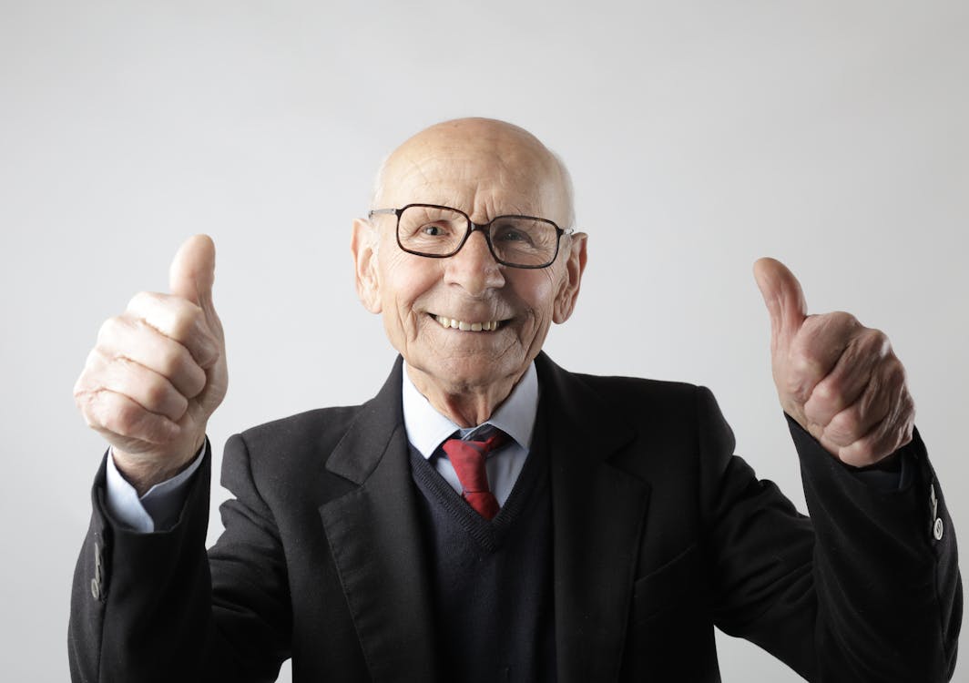 Free Positive senior man in eyeglasses showing thumbs up and looking at camera Stock Photo