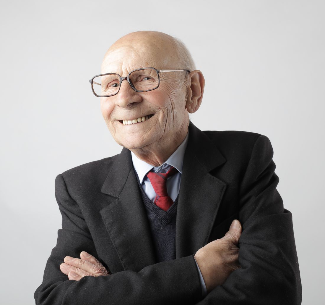 Portrait of a cheerful elderly man wearing glasses and a formal suit