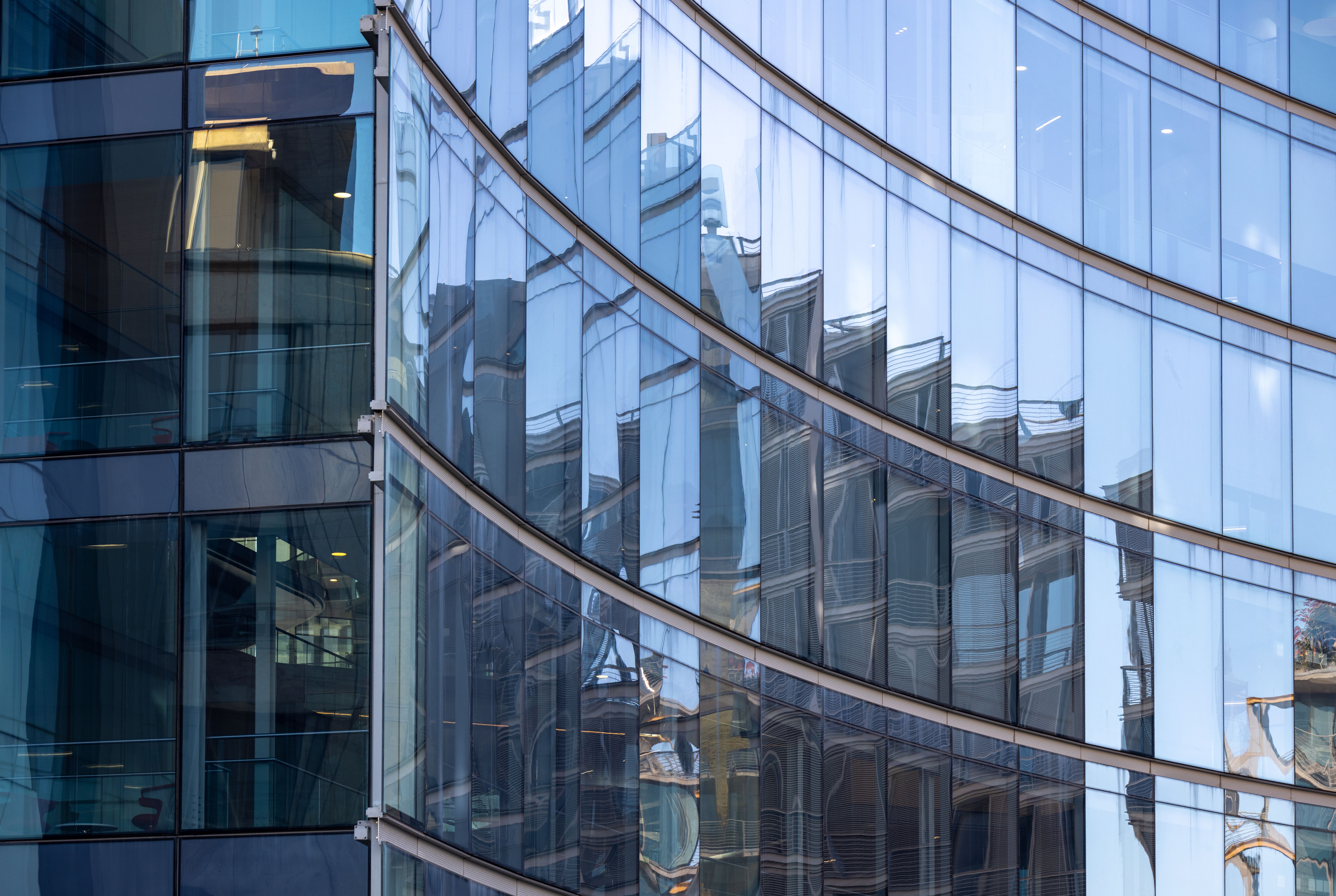 Modern curved glass facade reflecting surrounding buildings