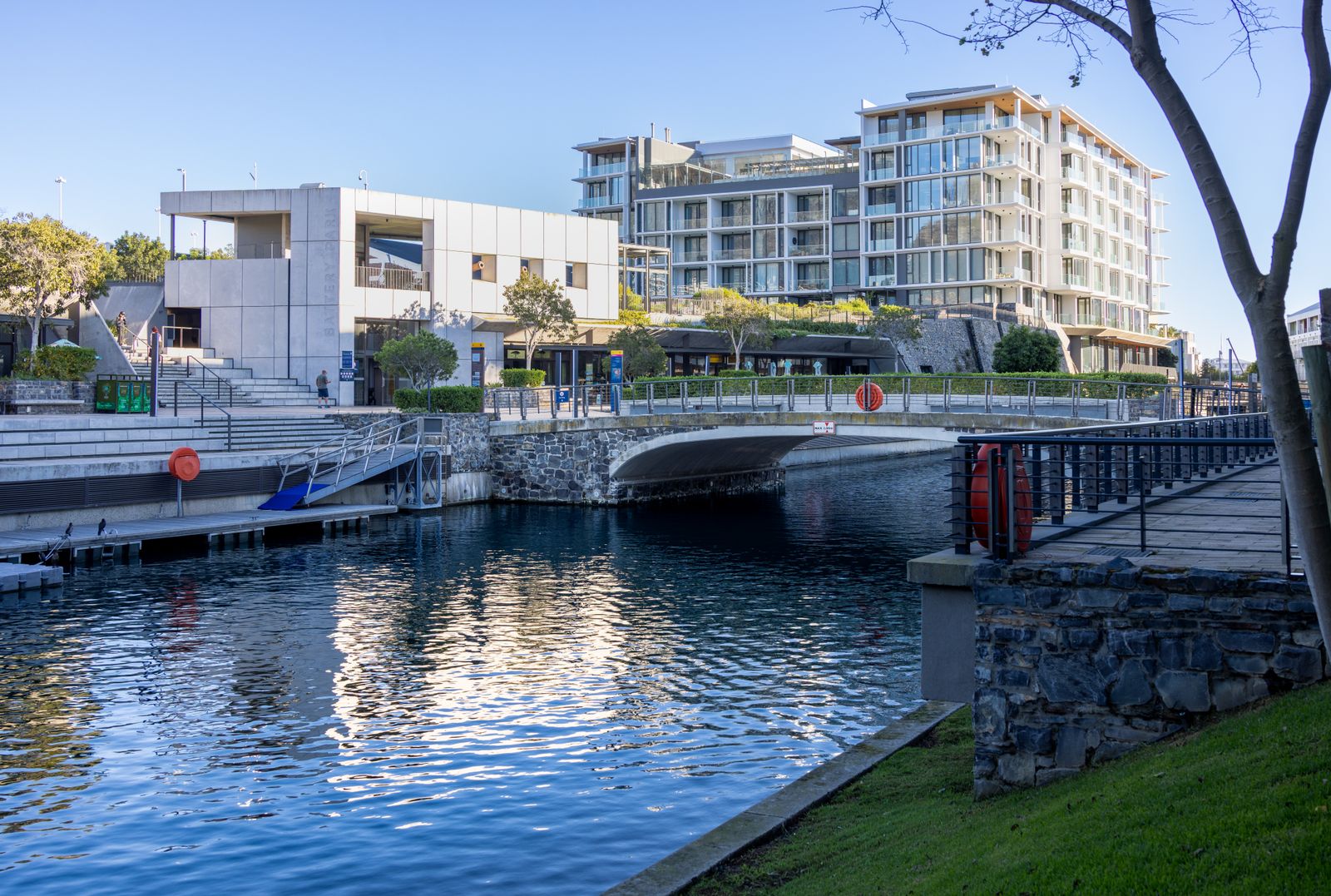 Modern mixed-use buildings along a landscaped waterfront canal