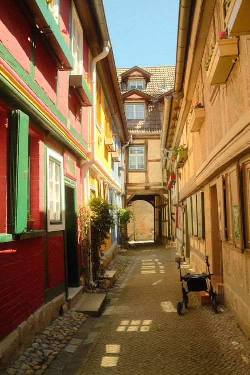 Free A quaint cobblestone alley in Quedlinburg, Germany, with colorful historic buildings and bright sunlight. Stock Photo