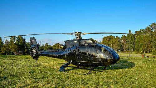 Free A sleek black helicopter resting on a grassy field in Võsu, Estonia on a clear day. Stock Photo