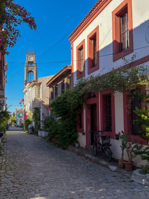 Free Picturesque cobblestone street with classic architecture under a clear blue sky, featuring a historic clock tower. Stock Photo