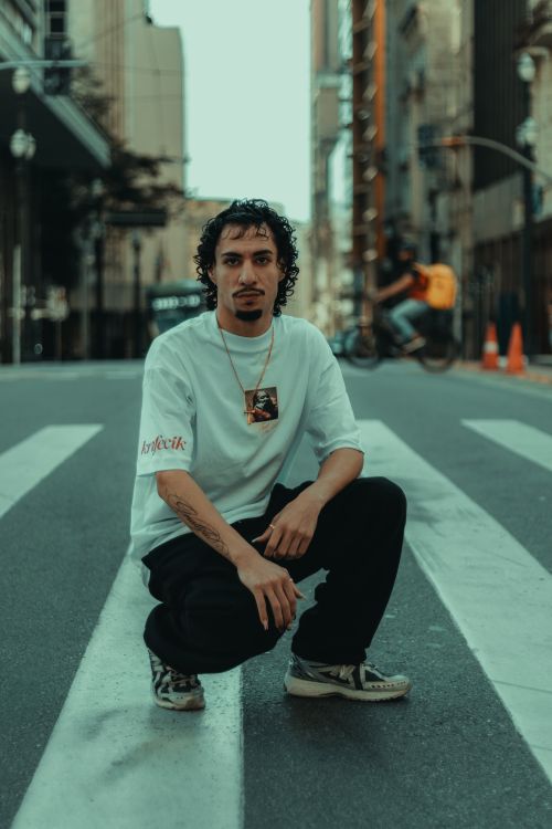 Free Stylish urban portrait of a man kneeling on a city street crosswalk. Stock Photo