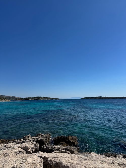 Free Tranquil ocean view with clear blue skies and rocky shore, ideal for travel and nature concepts. Stock Photo