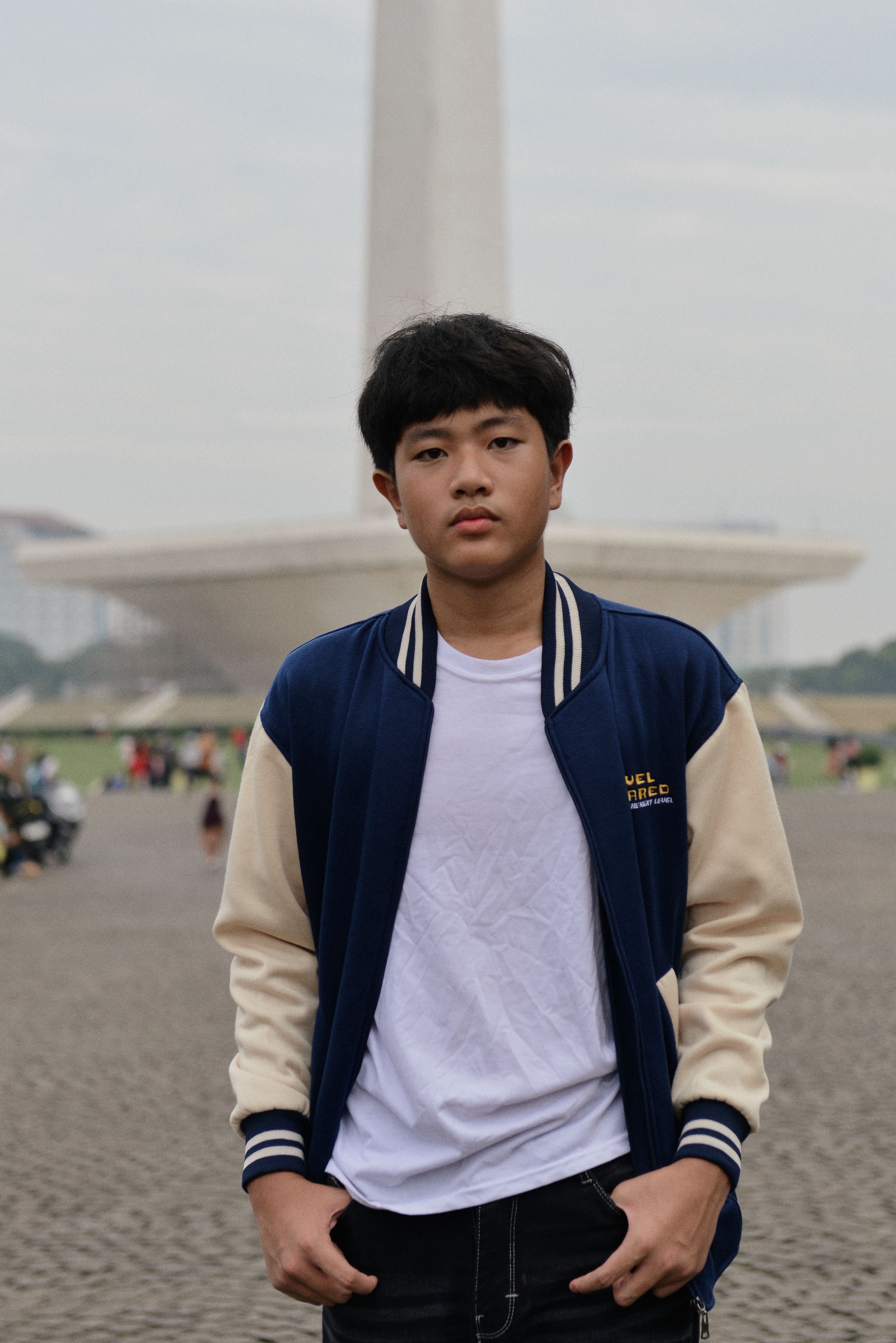 Teenage boy in casual wear posing with a city monument in the background.