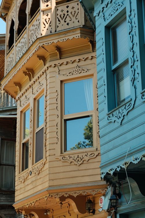Free Close-up of a Victorian-style building facade with intricate wood detailing under sunlight. Stock Photo