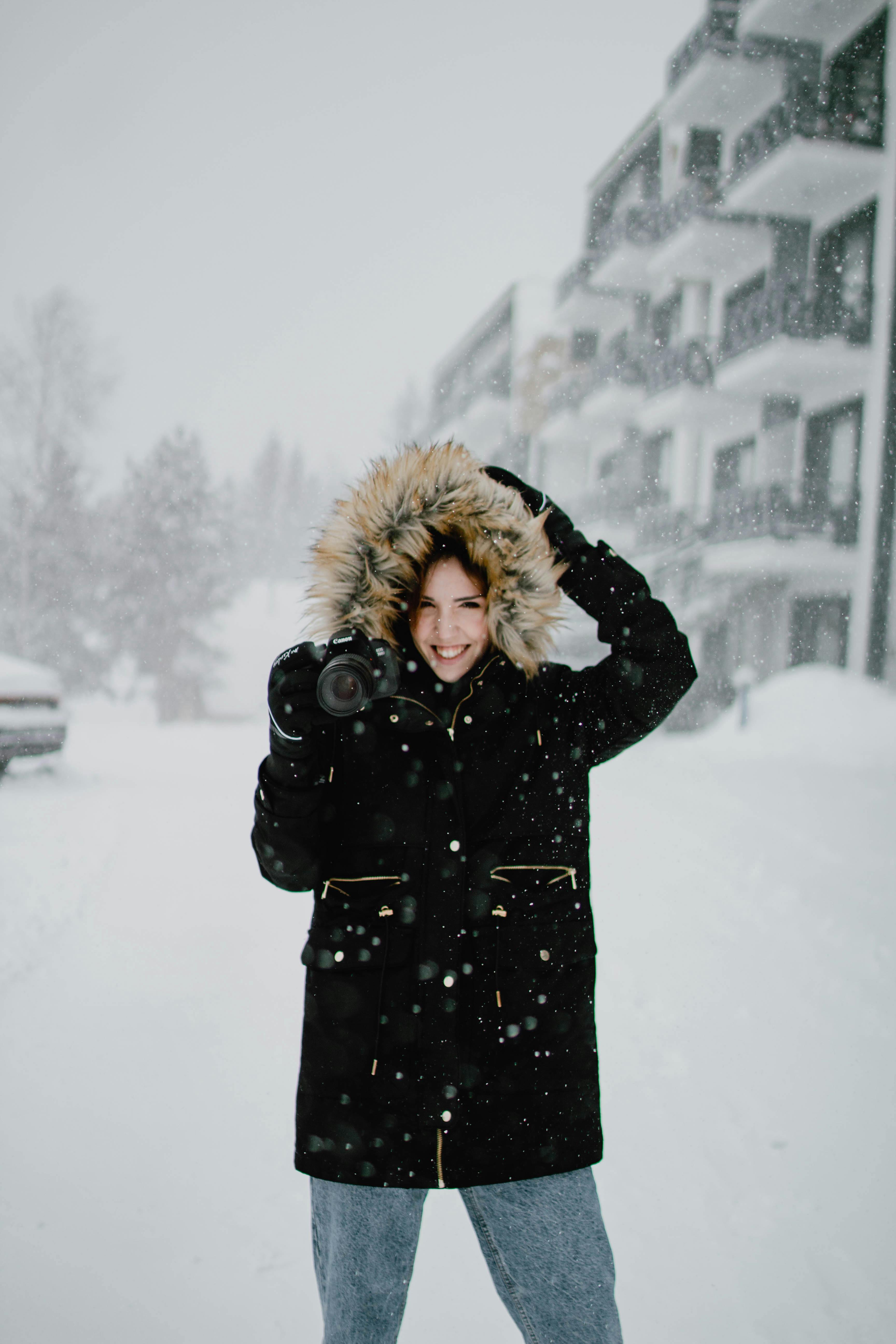 woman in black coat standing on snow covered ground