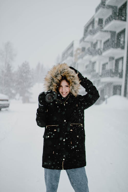 Woman in Black Coat Standing on Snow Covered Ground