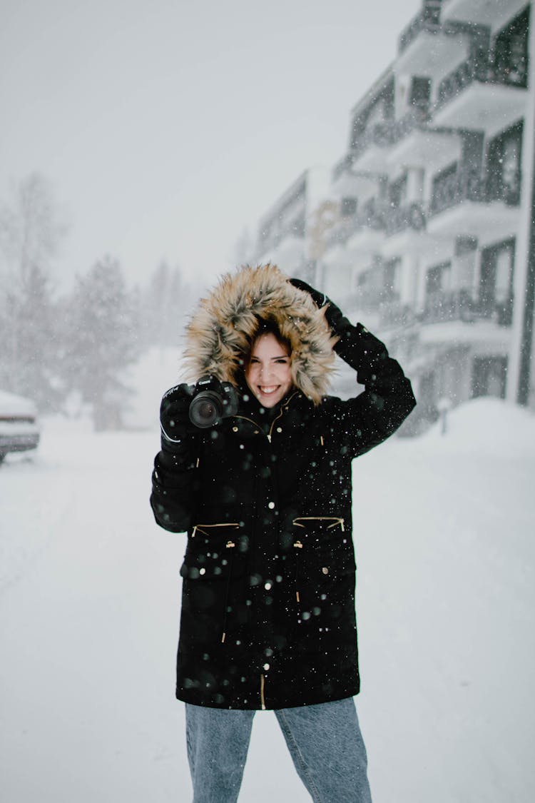 Woman In Black Coat Standing On Snow Covered Ground