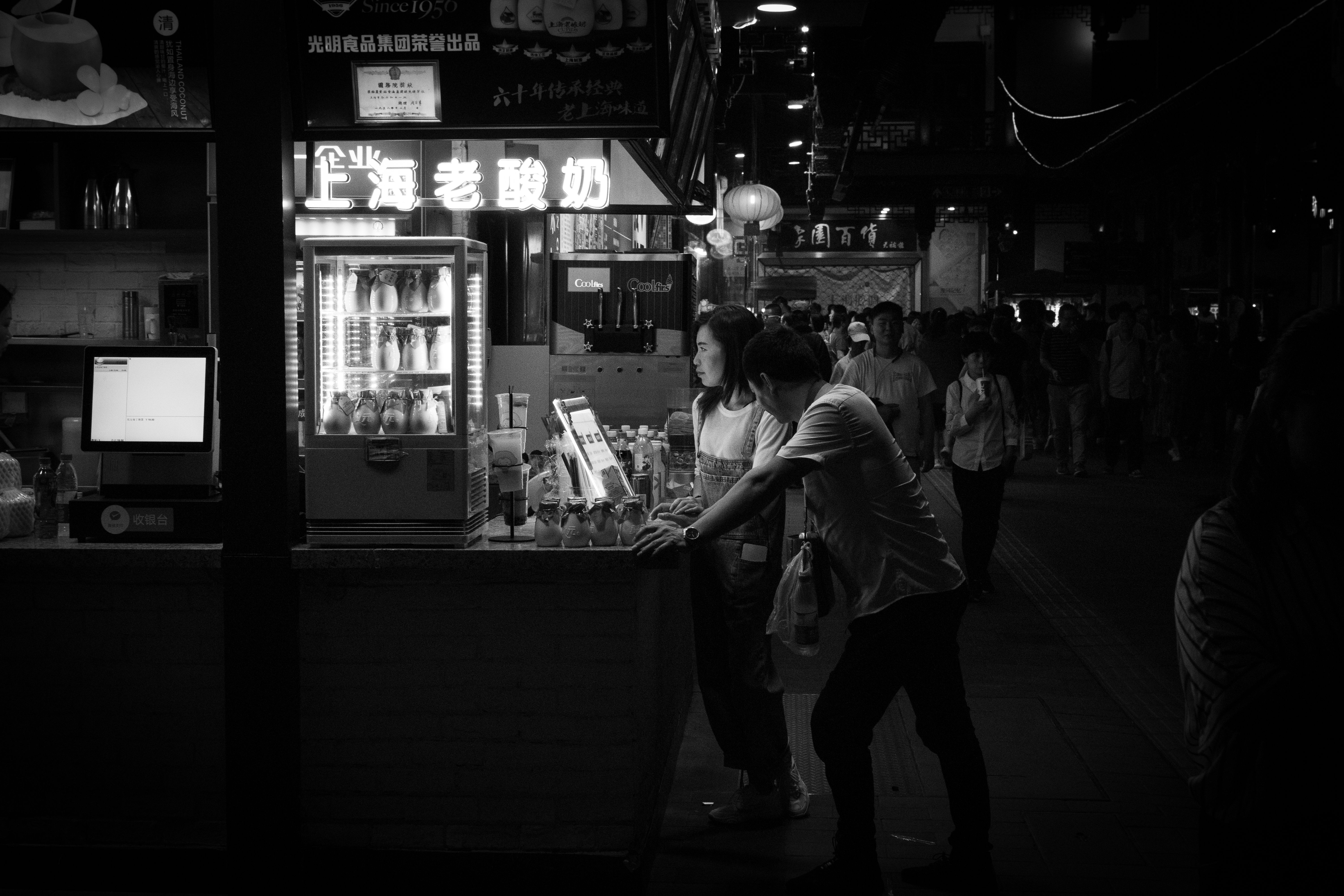 A bustling, crowded street market in Shanghai, China, with people walking closely, illustrating areas where petty theft might occur.