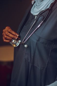 Close-up of a healthcare professional holding a stethoscope, focusing on medical attire and equipment.